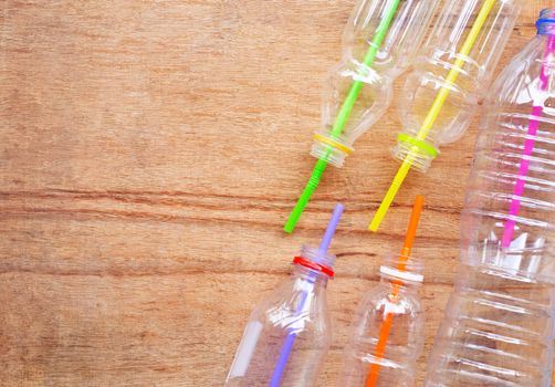 Plastic waste, Plastic bottles with straws on wooden background.
