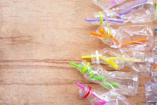 Plastic waste, Plastic bottles with straws on wooden background.