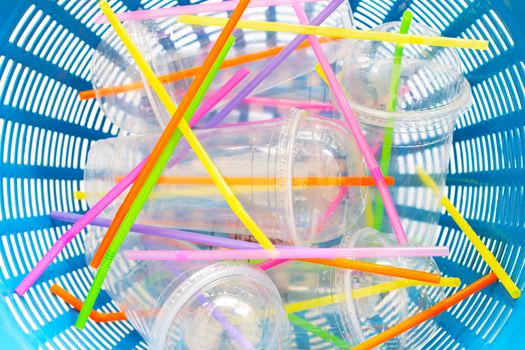 Plastic cups with straws in waste basket. top view