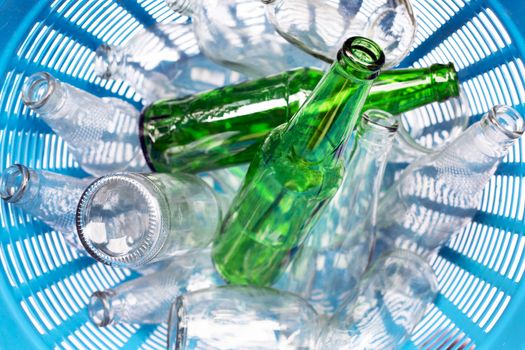 Glass bottles in blue waste basket.