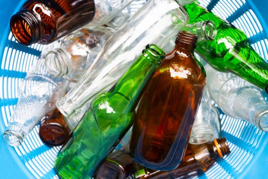 Glass bottles in blue waste basket.