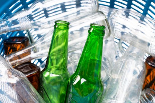 Glass bottles in blue waste basket.