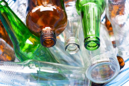 Glass bottles in blue waste basket.