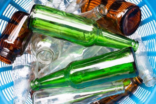 Glass bottles in blue waste basket.