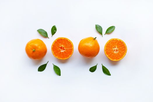 Orange fruits and green leaves on a white background. Top view