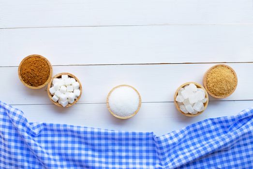 Various types of sugar on white wooden background.