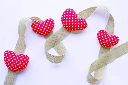 Valentine's hearts on burlap ribbon on white background. Top view