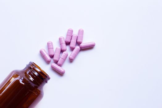 Bottle with purple medicine capsules pills on white