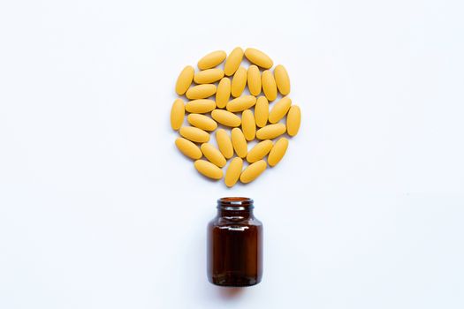 Vitamin C bottle and pills with orange fruit on white background