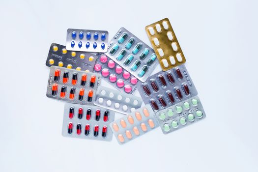 Various capsule medicines, pills and tablets in blister pack on white background.