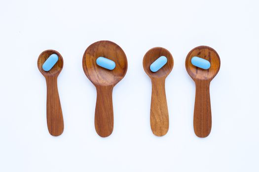 Medical blue pills with he wooden spoon on white background. Copy space