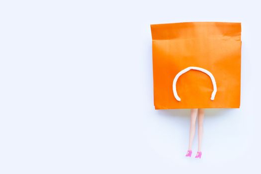 Woman doll  legs with paper shopping bag on white background. Copy space