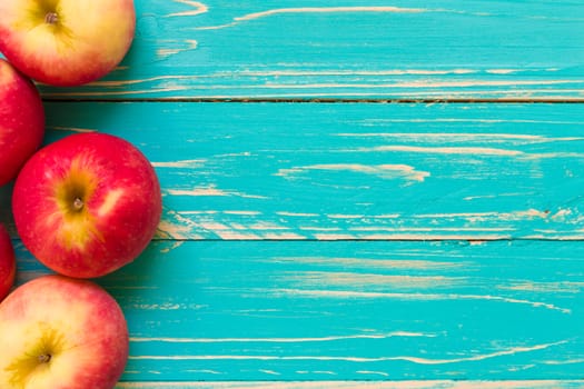 Group of red apple on blue wooden background.