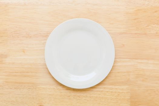 Empty plate without spoon and fork on table background.