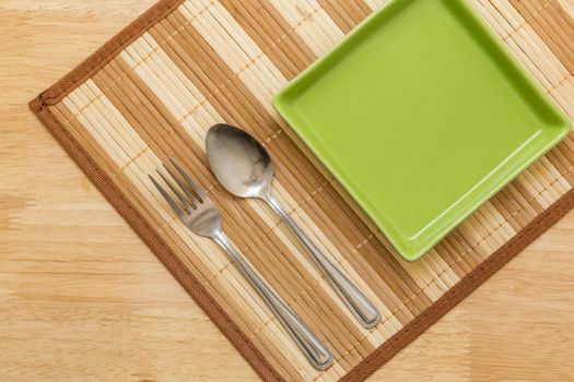 Empty plate with spoon and fork on table background.