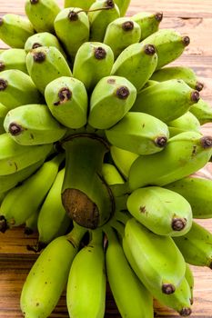 Bunch of unripe banana on wooden background.