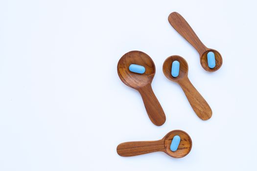 Medical blue pills with he wooden spoon on white background. Copy space