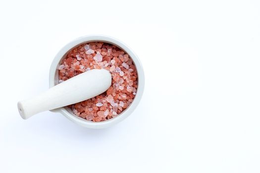 Pink himalayan salt in mortar with pestle on with background. Copy space