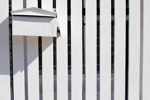 White post box on white wooden fence