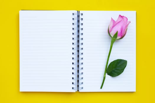 Diary notebook with rose on yellow background. Copy space