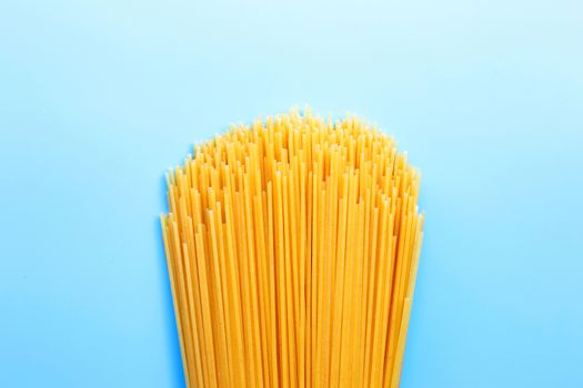 Yellow long spaghetti on blue background. Copy space