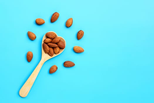 Almonds with wooden spoon on blue background. Copy space