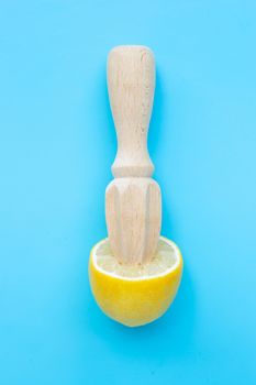 Fresh lemon with wooden juicer on blue background. 