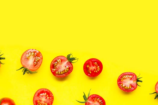 Fresh cherry tomatoes, whole and half cut isolated on yellow background. Copy space