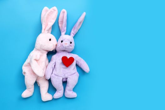 Rabbit toys kissing with red heart on blue background. Valentine's Day, Copy space