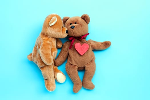 Brown bear toys kissing with red heart on blue background. Valentine's Day, Copy space