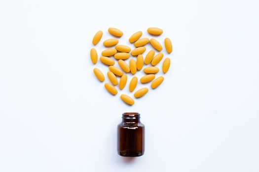 Vitamin C bottle and pills with orange fruit on white background