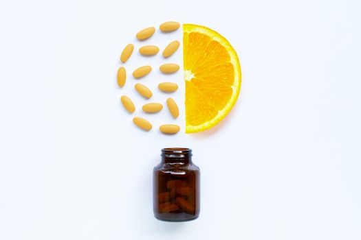 Vitamin C bottle and pills with orange fruit on white background