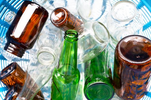 Glass bottles in blue waste basket.