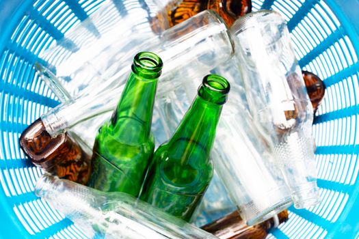 Glass bottles in blue waste basket.