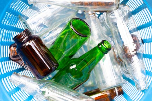 Glass bottles in blue waste basket.