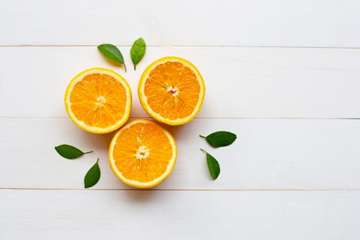 Fresh orange citrus fruit with leaves on white wooden background.