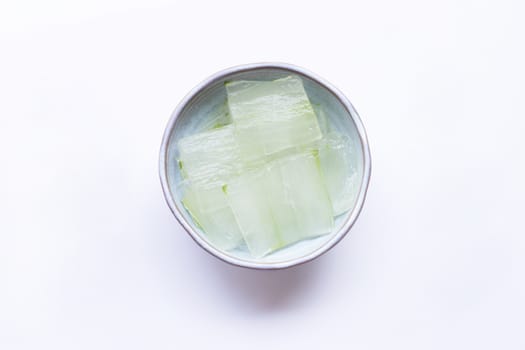 Aloe vera gel slices in ceramic bowl on white background.