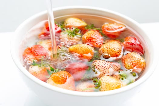 Strawberries soaked in water. Washing fresh fruit on white background.
