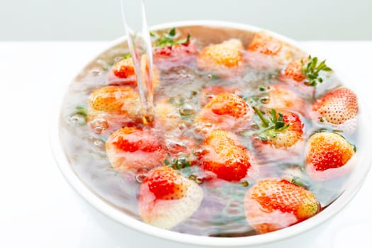 Strawberries soaked in water. Washing fresh fruit on white background.
