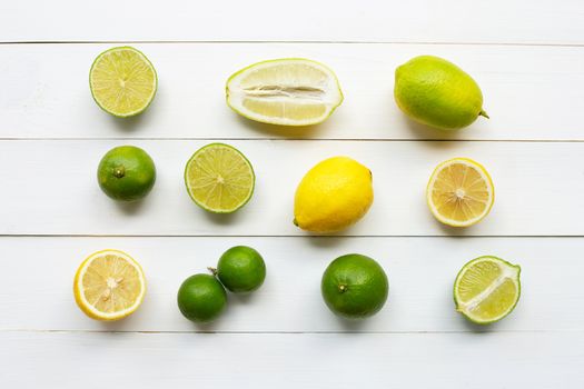 Ripe lemons and limes on white wooden background.