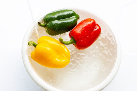 Bell pepper soaked in water. Washing fresh vegetables on white background.