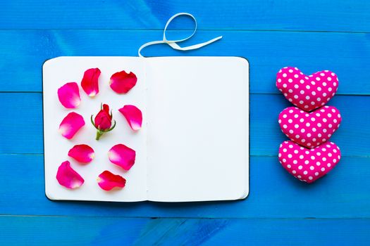 Diary notebook with rose and valentine's hearts on blue wooden background. Concept for Valentine's Day
