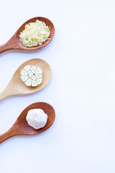 Garlic on wooden spoon on white background