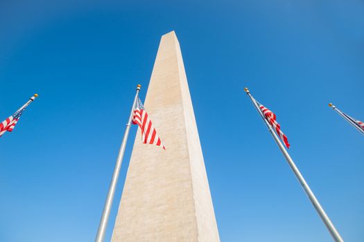 Washington Monument tall obelisk in National Mall Washington DC commemorating George Washington with flags around base.