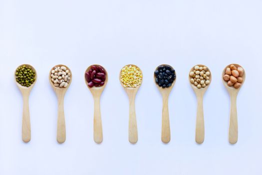 Different beans, legumes on wooden spoon on white background.