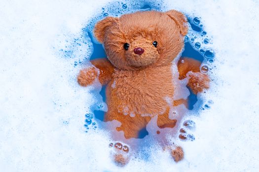 Soak  toy bear in laundry detergent water dissolution before washing.  Laundry concept, Top view