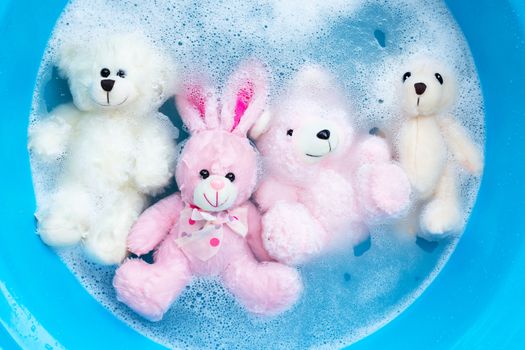 Soak rabbit doll with  toy bears in laundry detergent water dissolution before washing.  Laundry concept, Top view