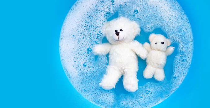 Soak toy bear in laundry detergent water dissolution before washing.  Laundry concept, Top view