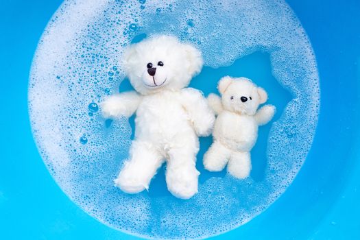 Soak toy bears in laundry detergent water dissolution before washing.  Laundry concept, Top view