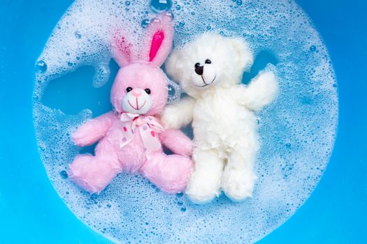 Soak rabbit doll with  toy teddy bear in laundry detergent water dissolution before washing.  Laundry concept, Top view